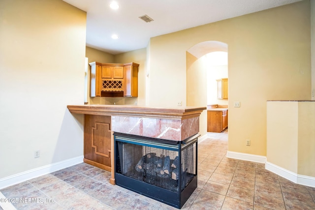 interior space featuring recessed lighting, baseboards, visible vents, arched walkways, and a multi sided fireplace