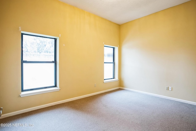 carpeted empty room with a textured ceiling and baseboards