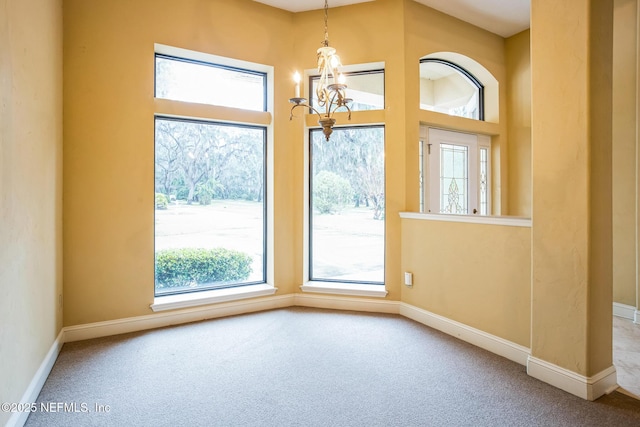 empty room with a healthy amount of sunlight, carpet, baseboards, and a notable chandelier