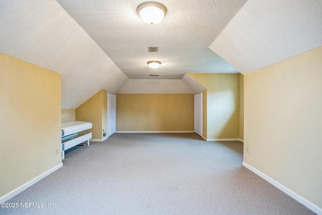 additional living space with carpet, visible vents, vaulted ceiling, and baseboards