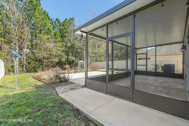 view of patio / terrace with a sunroom, a fenced backyard, and an outdoor structure