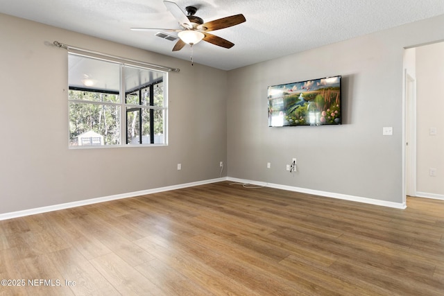 unfurnished room with light wood-type flooring, ceiling fan, visible vents, and a textured ceiling