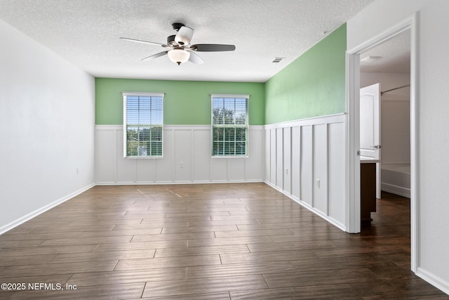 empty room with a ceiling fan, a textured ceiling, visible vents, and wood finished floors