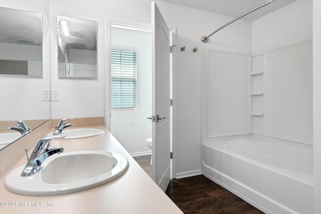 bathroom featuring  shower combination, a sink, toilet, and wood finished floors