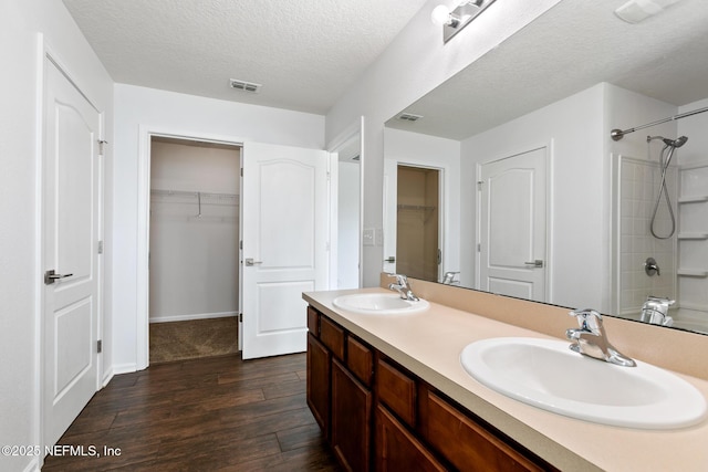 bathroom with visible vents, walk in shower, a sink, and wood finished floors