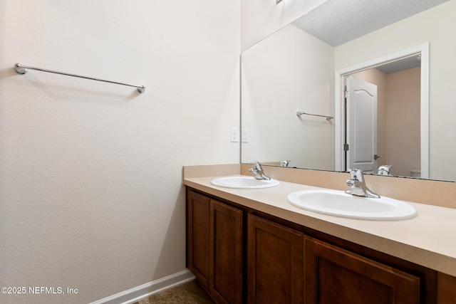 bathroom featuring double vanity, baseboards, and a sink