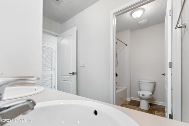 bathroom with a sink, a textured ceiling, toilet, and shower / bathtub combination