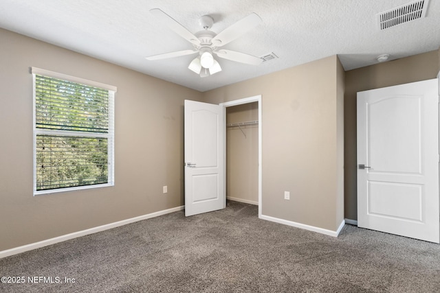 unfurnished bedroom featuring a textured ceiling, carpet floors, visible vents, and baseboards