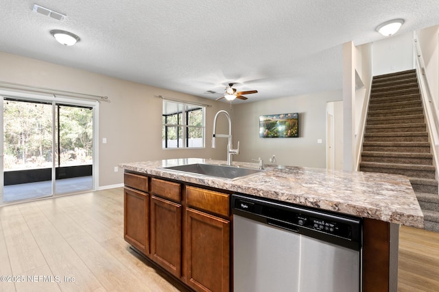 kitchen featuring light wood finished floors, visible vents, dishwasher, brown cabinets, and a sink