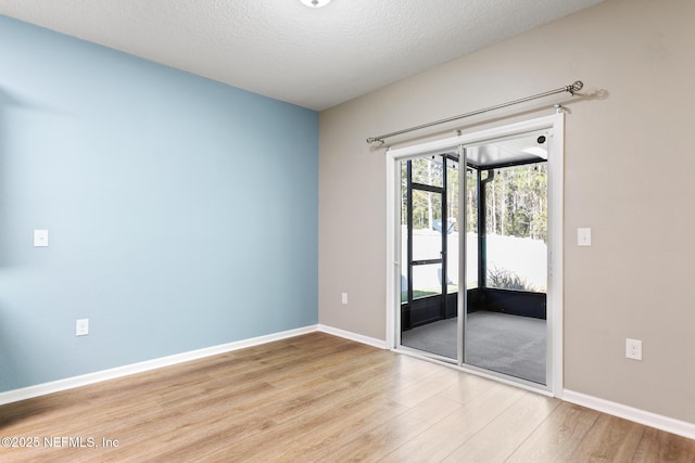 unfurnished room featuring a textured ceiling, wood finished floors, and baseboards