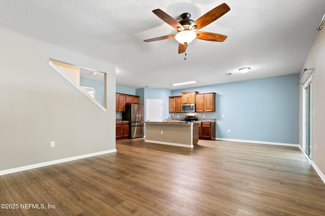 kitchen with open floor plan, appliances with stainless steel finishes, and wood finished floors