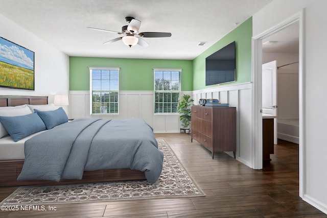 bedroom with a wainscoted wall, ceiling fan, wood finished floors, and visible vents