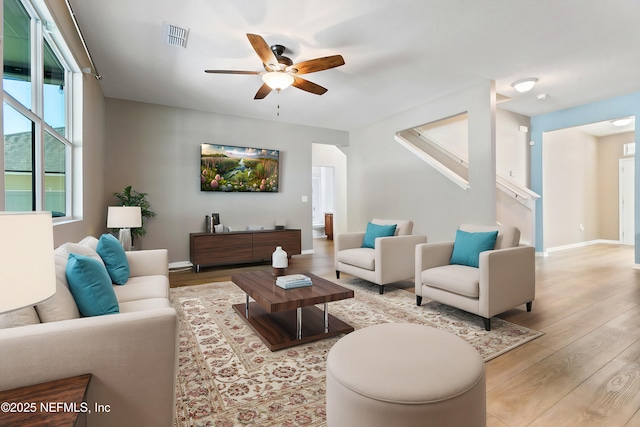 living room featuring baseboards, wood finished floors, visible vents, and a ceiling fan