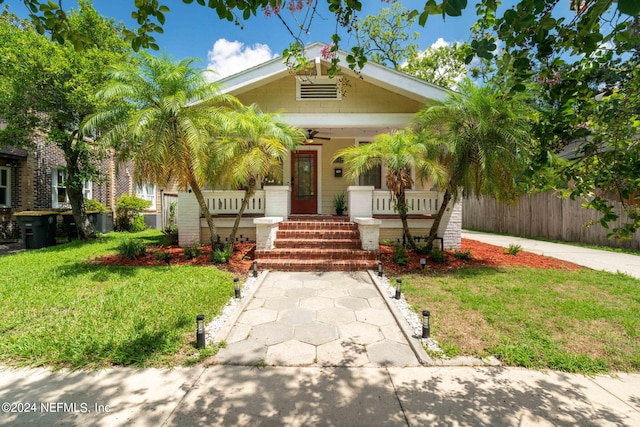 view of front of property with a ceiling fan, a front yard, covered porch, and fence