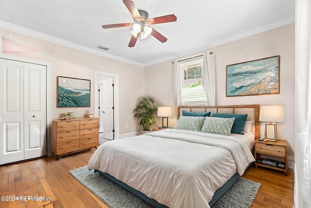 bedroom featuring baseboards, visible vents, ornamental molding, light wood-style floors, and a closet