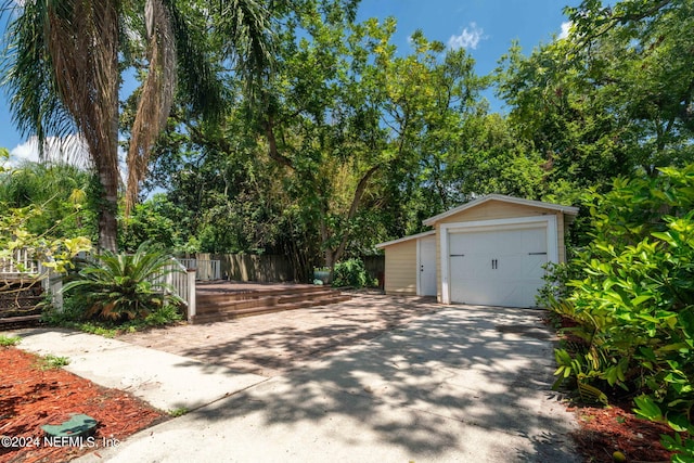 view of front of property featuring a garage, an outbuilding, driveway, and fence