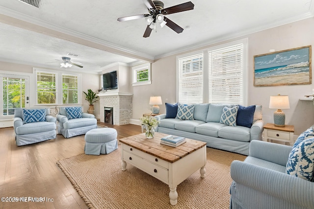 living room with a wealth of natural light, a brick fireplace, crown molding, and light wood finished floors