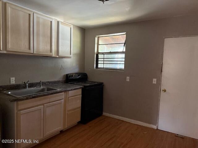 kitchen featuring a sink, dark countertops, black electric range oven, and wood finished floors