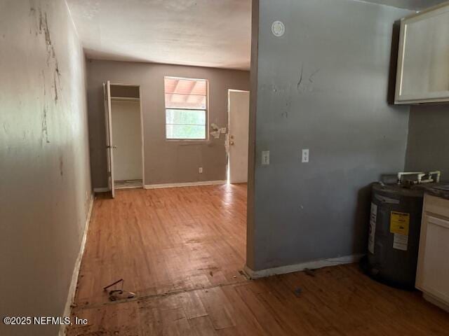 kitchen with light wood finished floors, baseboards, and electric water heater