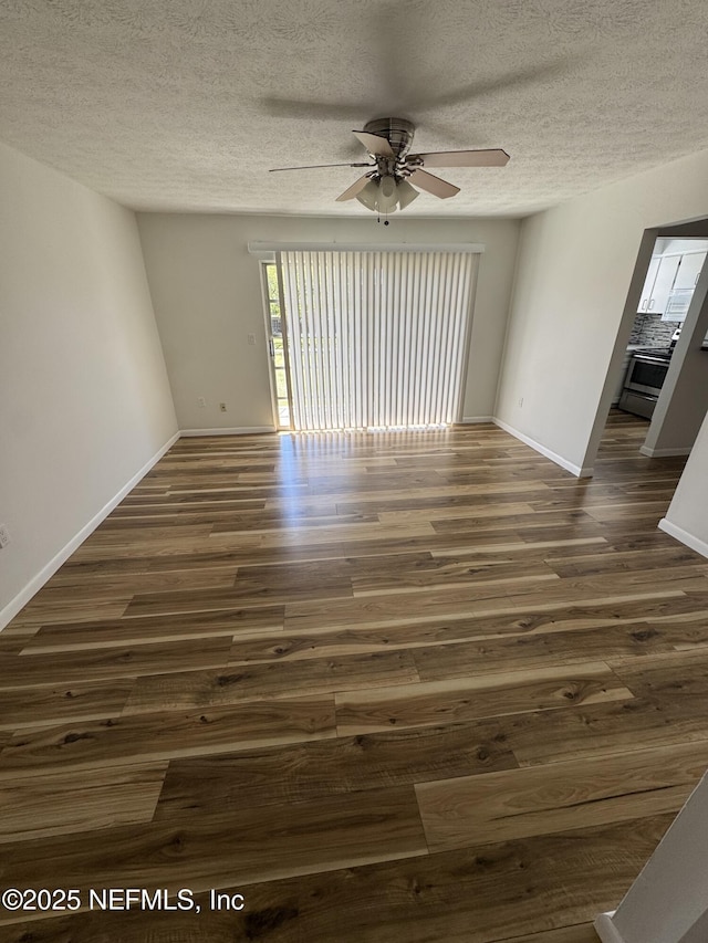 unfurnished room featuring a textured ceiling, dark wood-type flooring, and baseboards