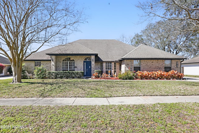 view of front facade featuring a front yard, brick siding, and roof with shingles