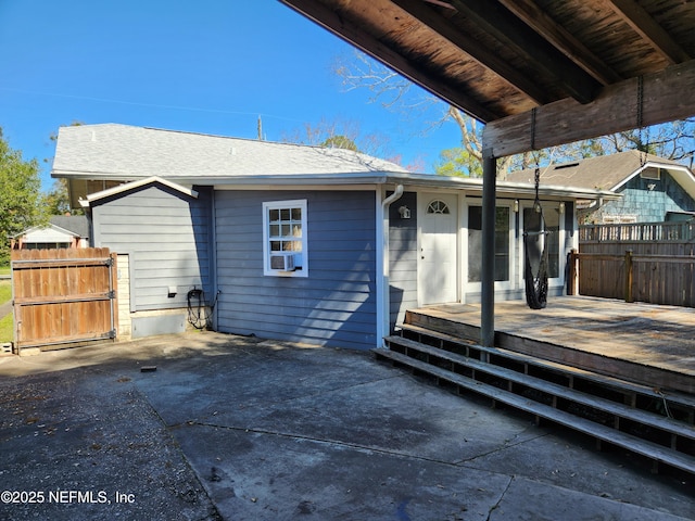 rear view of property featuring a patio area, fence, and a wooden deck