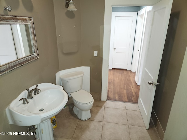 bathroom with baseboards, a sink, toilet, and tile patterned floors