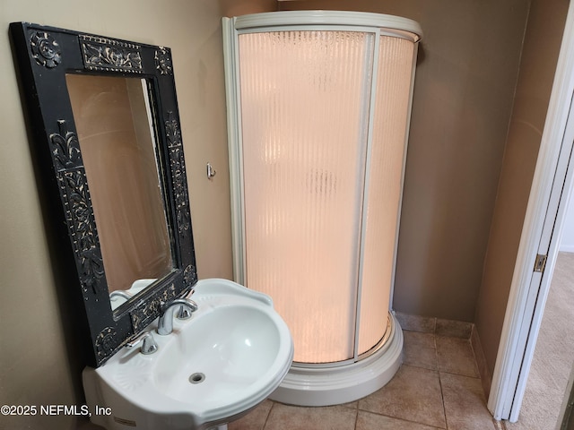 bathroom with a stall shower, tile patterned flooring, a sink, and baseboards