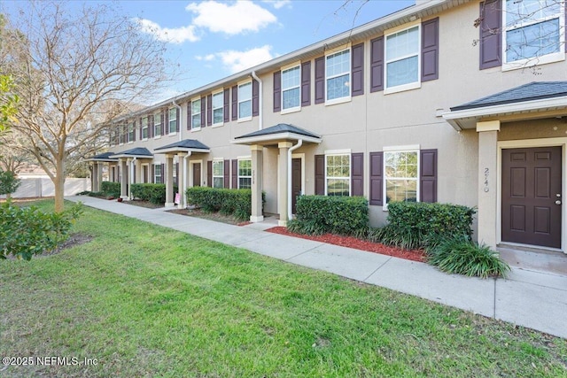 view of property featuring a front lawn and stucco siding