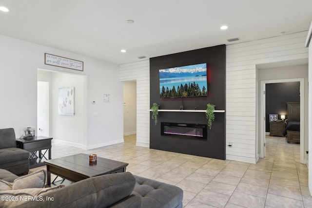 living area with light tile patterned flooring, recessed lighting, visible vents, and a glass covered fireplace