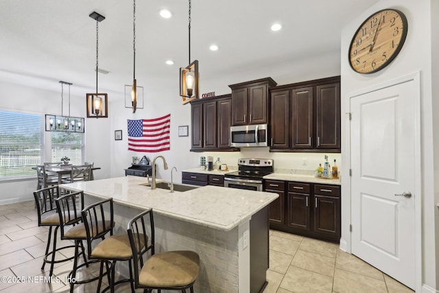 kitchen featuring appliances with stainless steel finishes, a breakfast bar, a sink, and decorative light fixtures