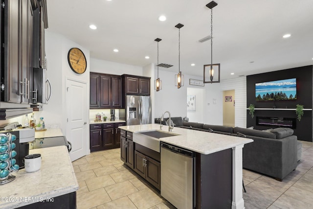 kitchen with appliances with stainless steel finishes, open floor plan, a sink, and dark brown cabinets