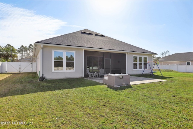 rear view of property featuring a yard, a patio, a shingled roof, a gate, and a fenced backyard