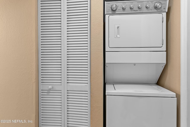 laundry area with stacked washer and dryer and a textured wall