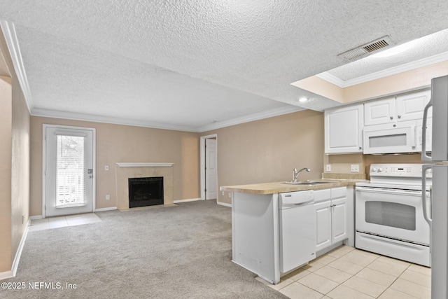 kitchen featuring visible vents, white cabinetry, a sink, white appliances, and a peninsula