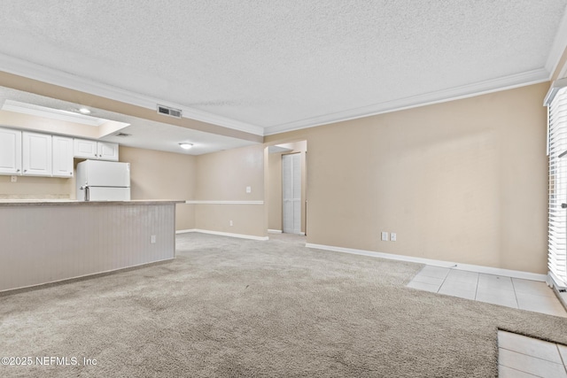 unfurnished living room with ornamental molding, light colored carpet, visible vents, and a textured ceiling