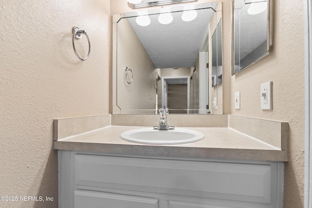 bathroom with a textured wall, a textured ceiling, and vanity