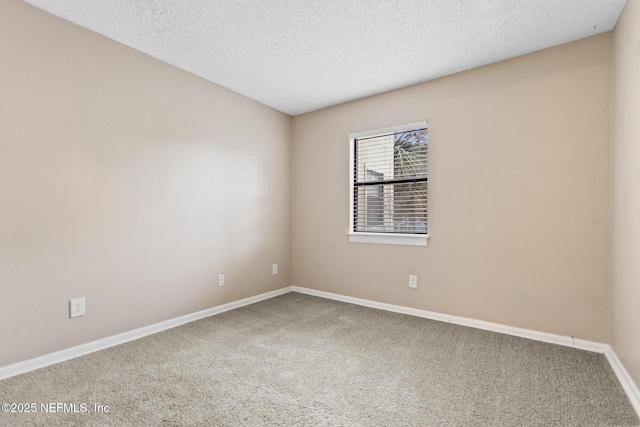 carpeted empty room with a textured ceiling and baseboards