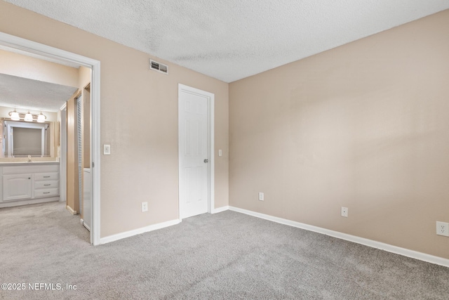 unfurnished bedroom featuring light carpet, baseboards, visible vents, and a textured ceiling