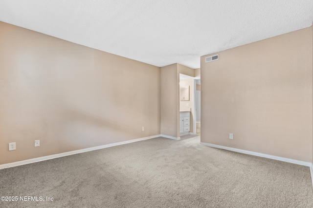 carpeted spare room with baseboards, visible vents, and a textured ceiling