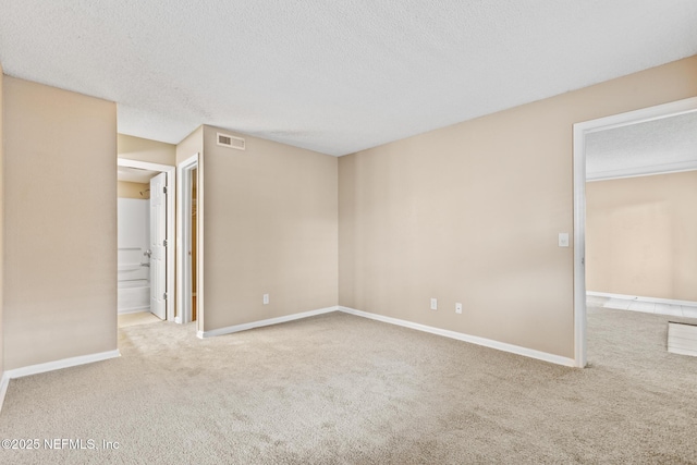 empty room with carpet floors, baseboards, visible vents, and a textured ceiling