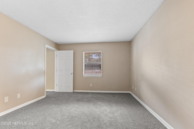 carpeted spare room with a textured ceiling and baseboards