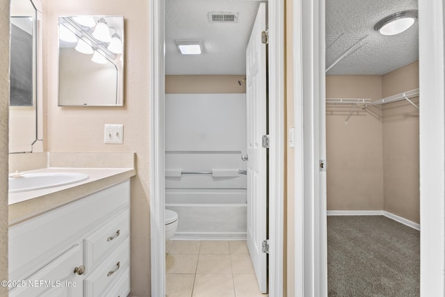 full bath with a walk in closet, visible vents, toilet, a textured ceiling, and vanity