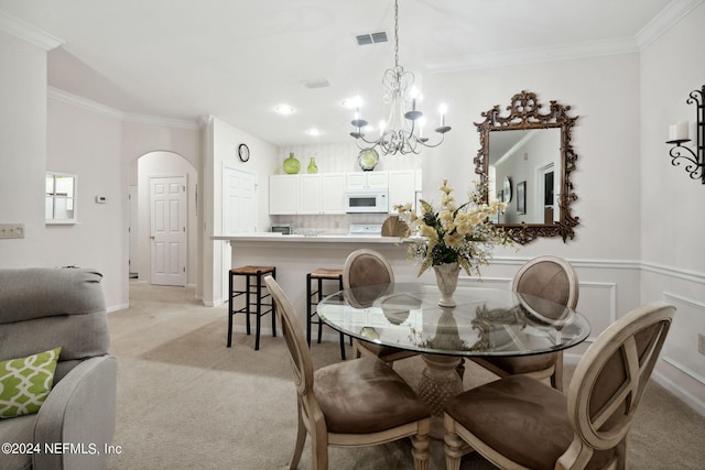 dining room featuring a wainscoted wall, ornamental molding, arched walkways, and light colored carpet