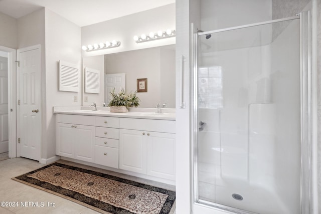 full bathroom featuring double vanity, a stall shower, a sink, and tile patterned floors