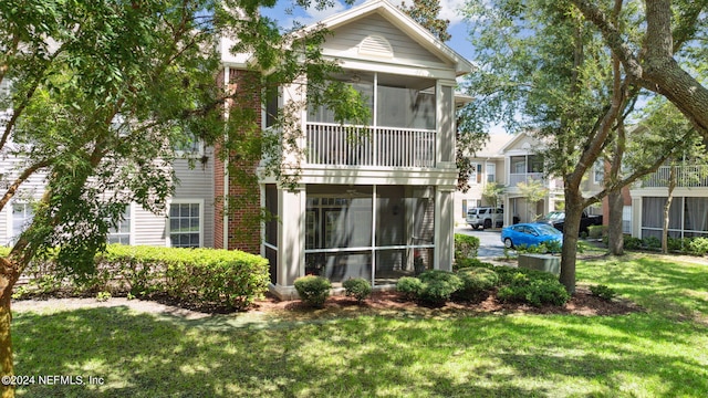 back of property with a lawn and a sunroom