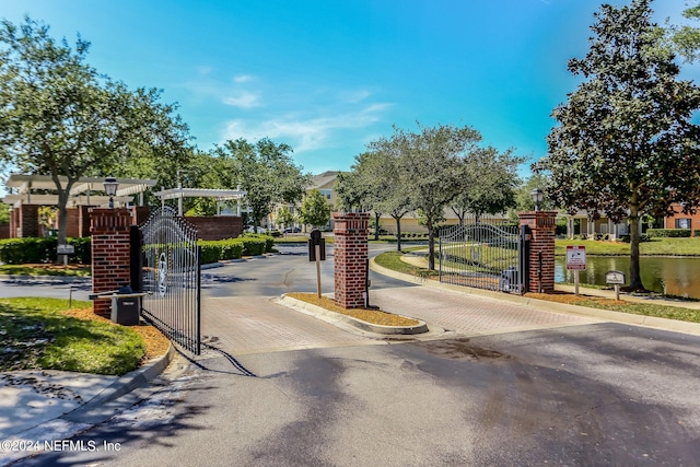 view of road with street lights, curbs, a gated entry, and a gate