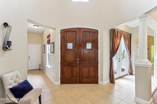 entryway with light tile patterned floors, baseboards, and ornate columns