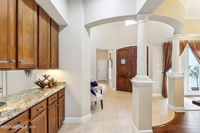 interior space featuring decorative columns, baseboards, and a high ceiling