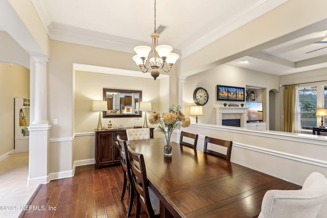 dining space with dark wood finished floors, a fireplace, ornate columns, and a chandelier